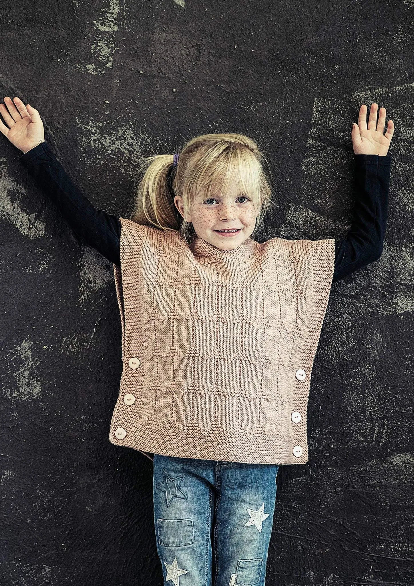 Strikket børneponcho med knapper i siderne